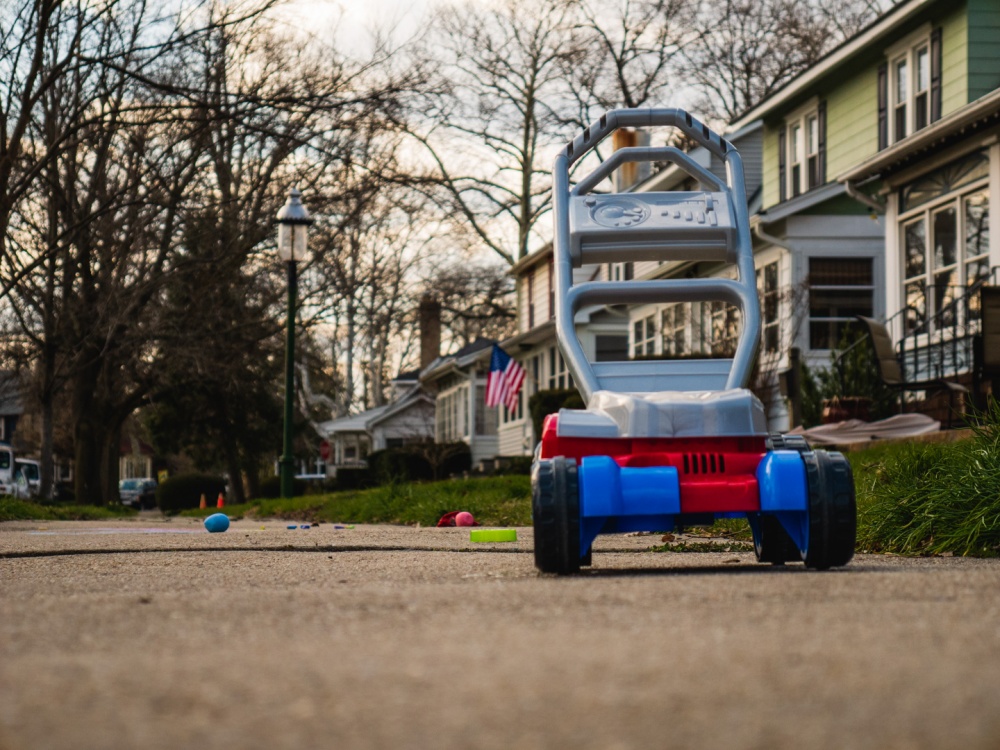 A toy mower out on the sidewalk